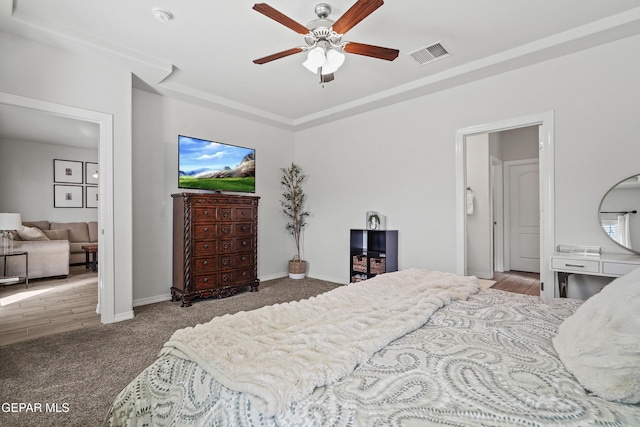 bedroom featuring a tray ceiling, a ceiling fan, visible vents, and baseboards