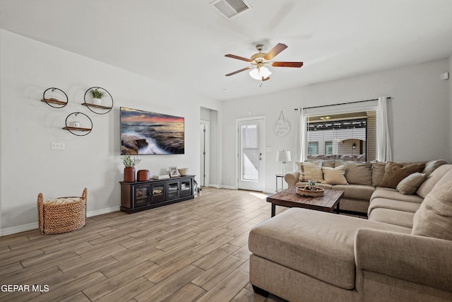 living room featuring baseboards, light wood-style flooring, visible vents, and a ceiling fan