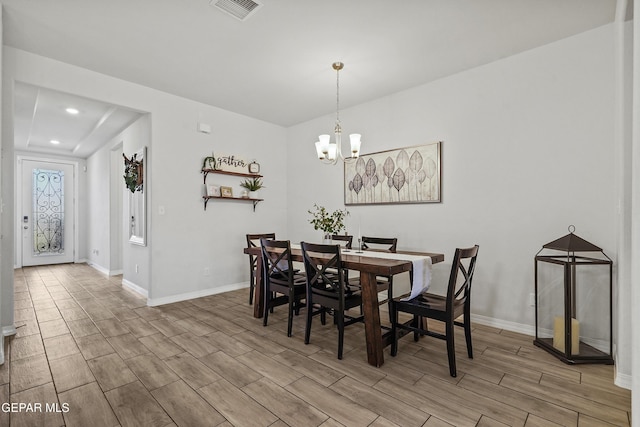 dining space featuring a notable chandelier, wood tiled floor, visible vents, and baseboards