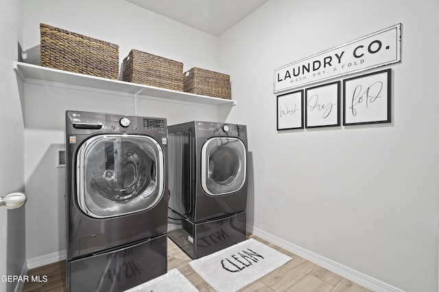 clothes washing area featuring laundry area, independent washer and dryer, and wood finished floors