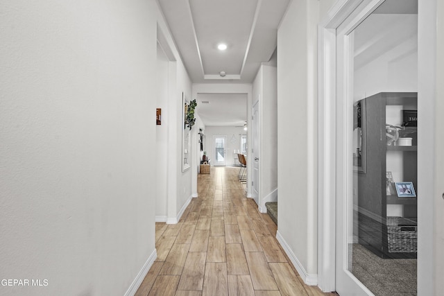 hallway featuring baseboards, stairway, and light wood-style floors