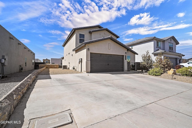 view of side of home featuring a garage, driveway, central AC, and stucco siding