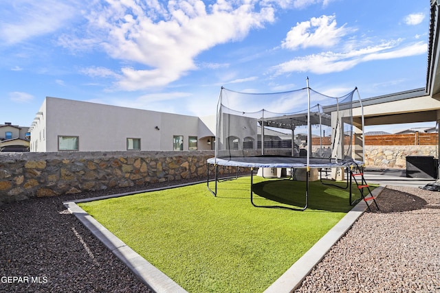 view of yard featuring a trampoline and a fenced backyard