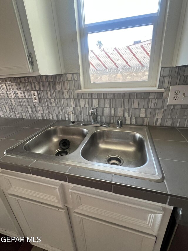 details featuring tile countertops, white cabinetry, and backsplash