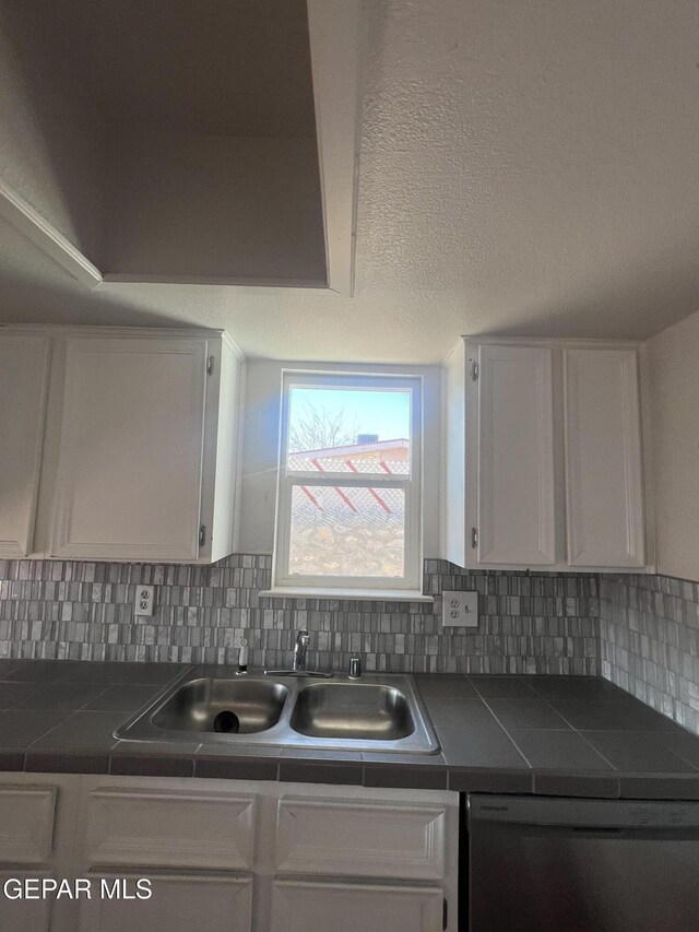 kitchen featuring a sink, dishwasher, tile counters, white cabinetry, and backsplash
