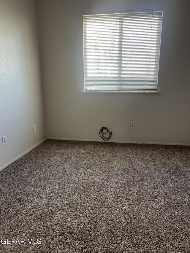 empty room featuring baseboards and carpet flooring