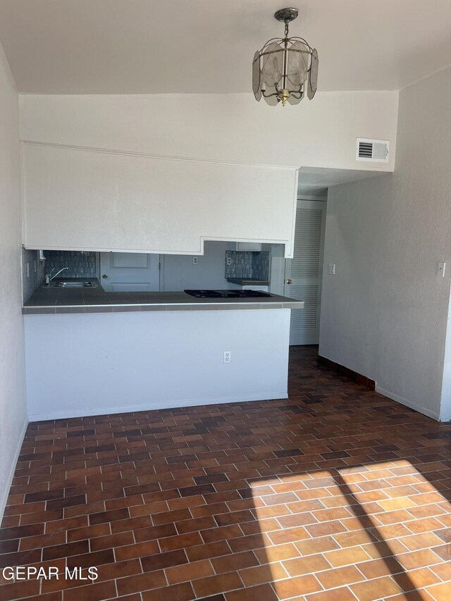 kitchen featuring dark countertops, a chandelier, decorative backsplash, gas stovetop, and visible vents