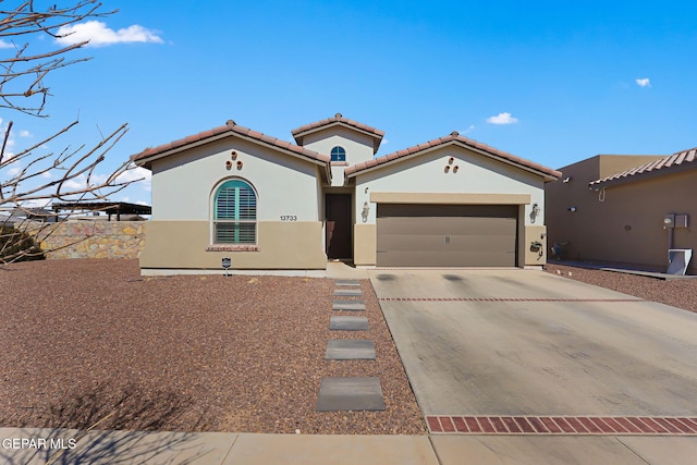 mediterranean / spanish home with a garage, a tile roof, concrete driveway, and stucco siding