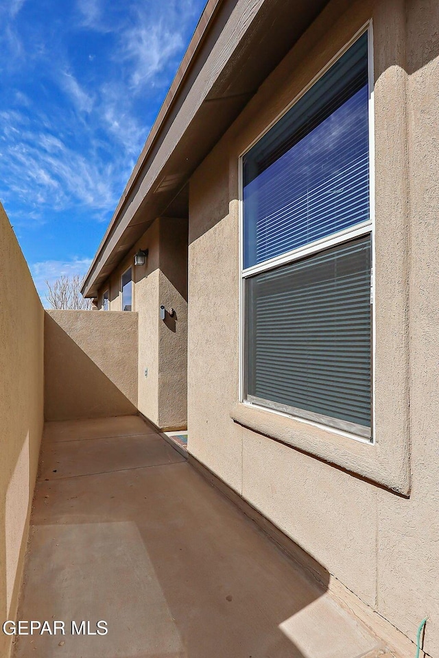 entrance to property featuring a patio, fence, and stucco siding