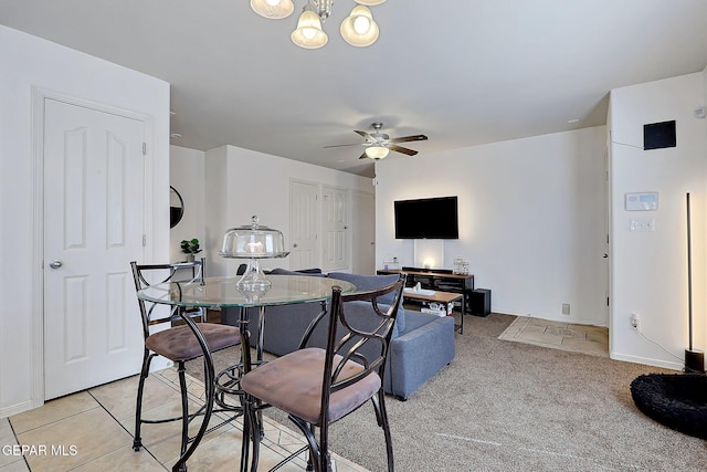 dining area with light colored carpet, baseboards, and ceiling fan with notable chandelier