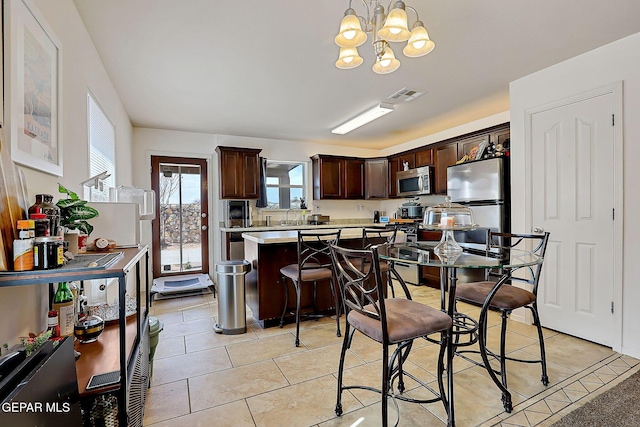 kitchen featuring dark brown cabinetry, visible vents, a kitchen island, stainless steel appliances, and light countertops