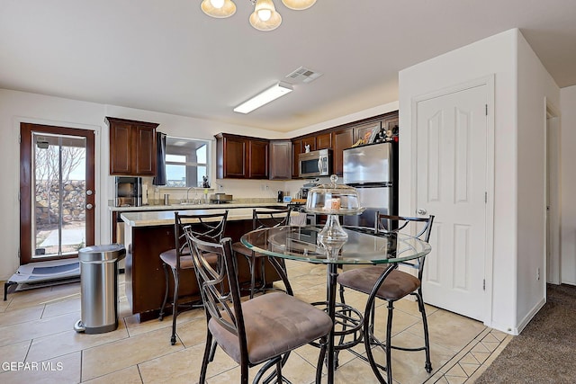 kitchen with light tile patterned floors, dark brown cabinetry, visible vents, light countertops, and appliances with stainless steel finishes