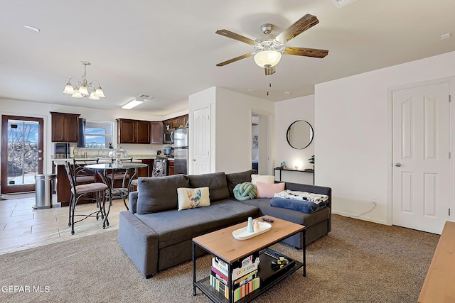 living room featuring ceiling fan with notable chandelier and light carpet