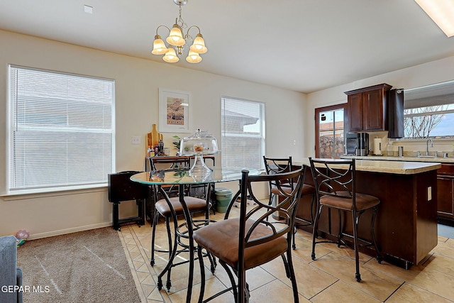 dining space featuring light carpet, baseboards, and a notable chandelier