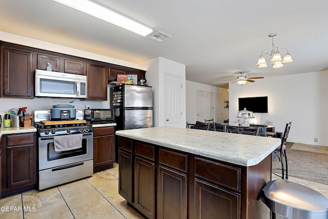 kitchen featuring visible vents, appliances with stainless steel finishes, decorative light fixtures, light countertops, and dark brown cabinets