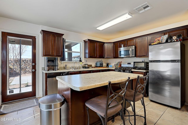 kitchen with visible vents, appliances with stainless steel finishes, light countertops, dark brown cabinets, and a sink