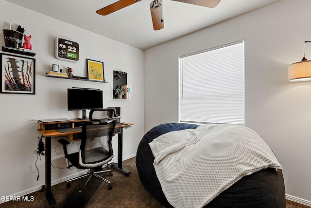 carpeted office space featuring ceiling fan and baseboards