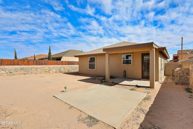 rear view of house with a patio, a fenced backyard, and stucco siding