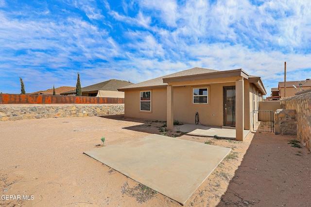 rear view of house featuring a patio area, a fenced backyard, and stucco siding