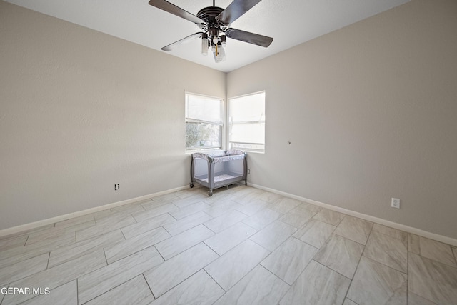 unfurnished room with ceiling fan and baseboards