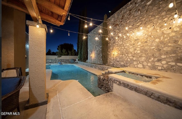 pool at night featuring a fenced in pool, a patio area, and a fenced backyard