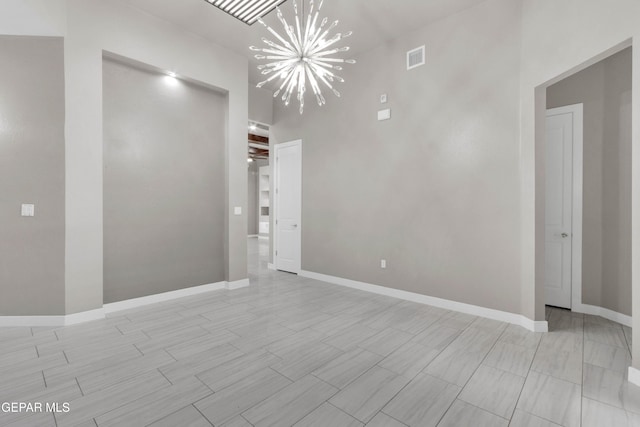 empty room with visible vents, baseboards, a notable chandelier, and wood finish floors