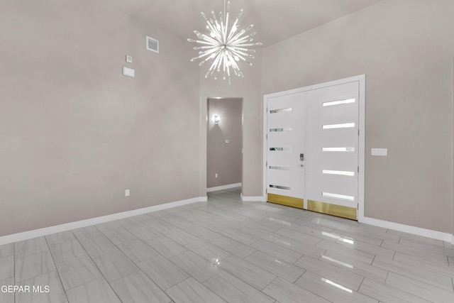 spare room featuring baseboards, visible vents, and a notable chandelier