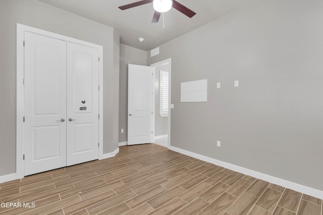 unfurnished bedroom with a closet, visible vents, a ceiling fan, wood tiled floor, and baseboards