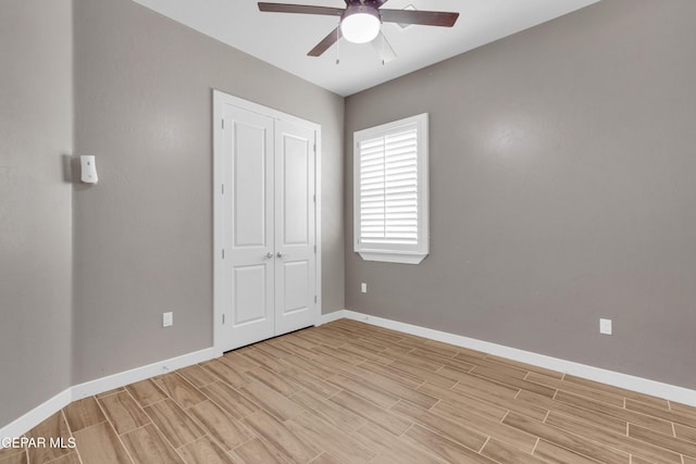 unfurnished bedroom featuring a ceiling fan, baseboards, a closet, and wood finish floors