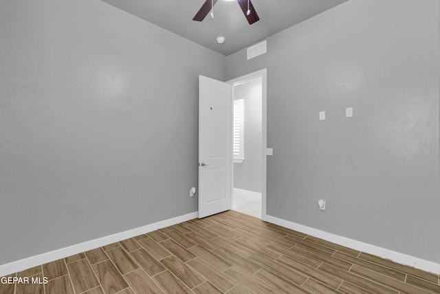 spare room featuring baseboards, a ceiling fan, visible vents, and wood tiled floor