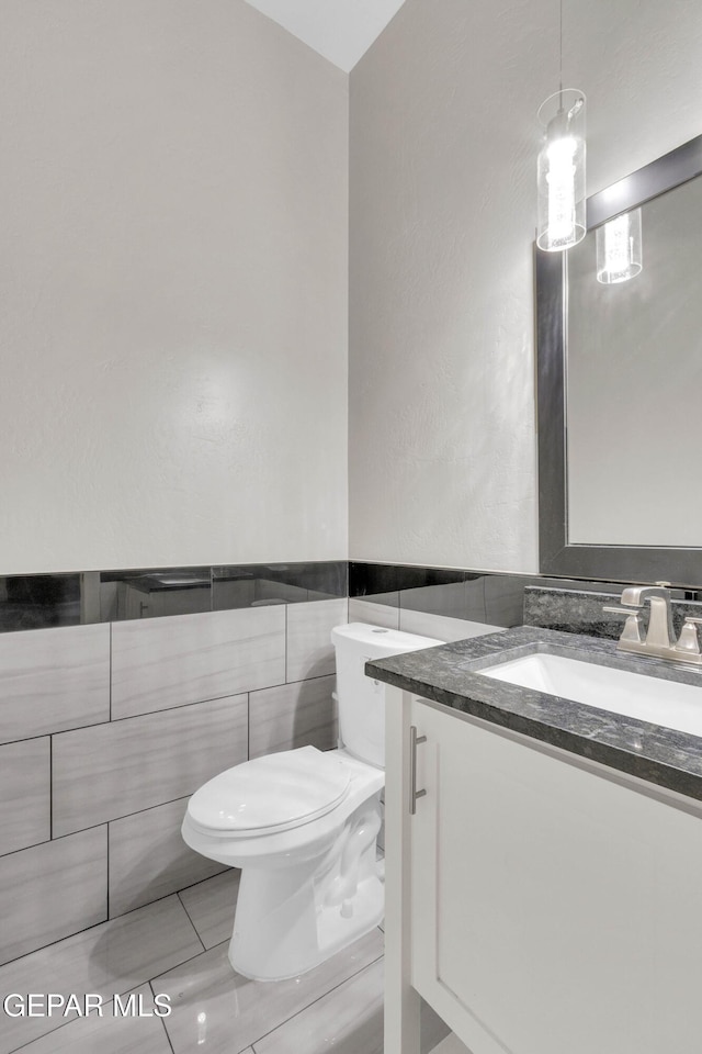 half bathroom with vanity, toilet, and tile walls