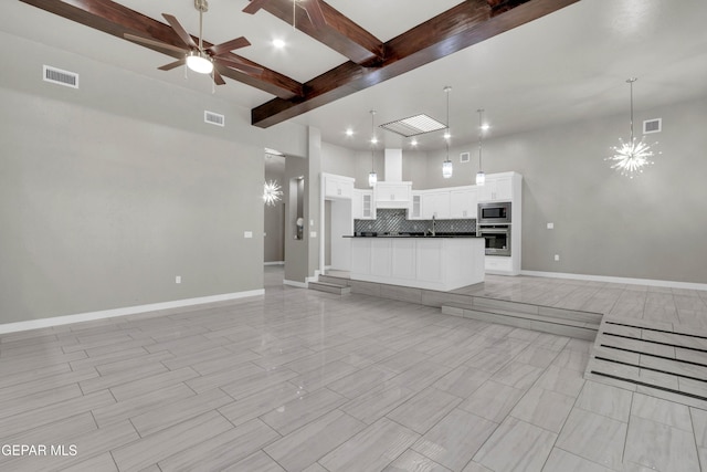 unfurnished living room with baseboards, visible vents, beam ceiling, and ceiling fan with notable chandelier