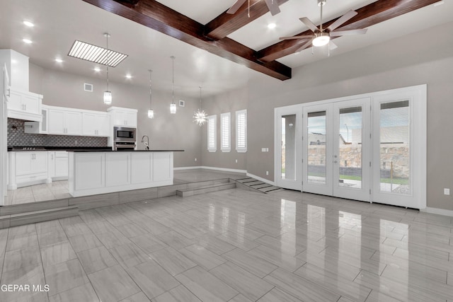 kitchen featuring stainless steel appliances, dark countertops, backsplash, open floor plan, and beamed ceiling