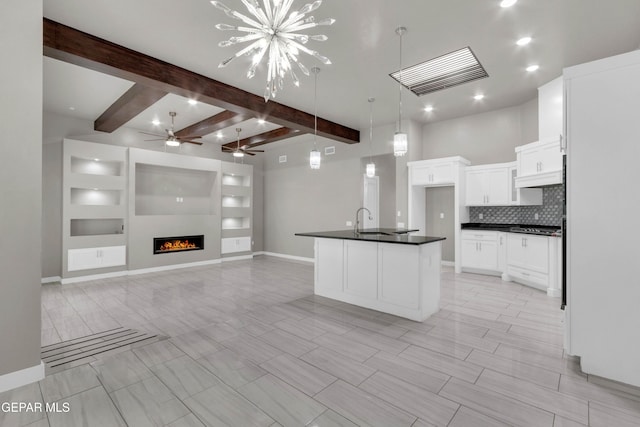 kitchen with tasteful backsplash, dark countertops, open floor plan, a fireplace, and white cabinetry