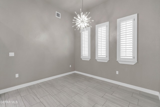 spare room with a chandelier, visible vents, and baseboards