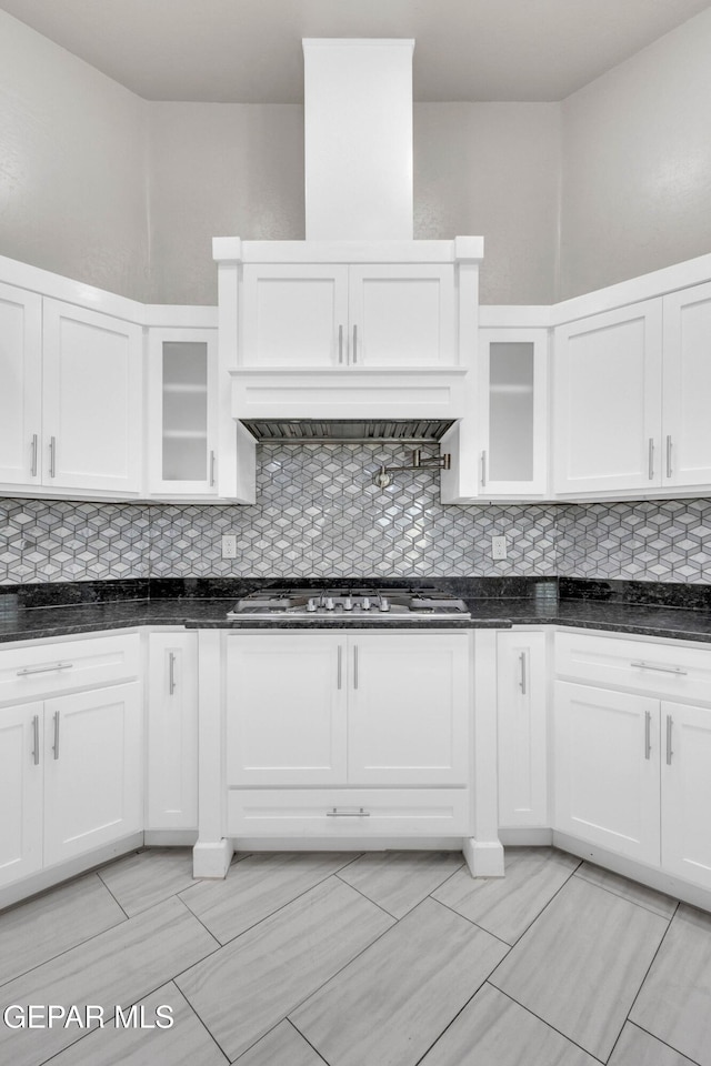 kitchen featuring stainless steel gas stovetop, white cabinetry, and backsplash