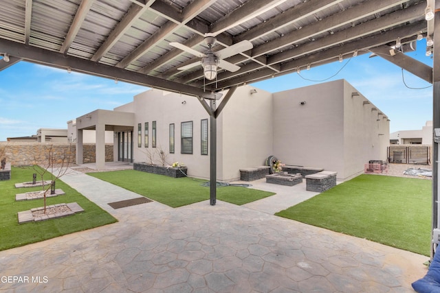 view of patio with ceiling fan, an outdoor fire pit, and fence