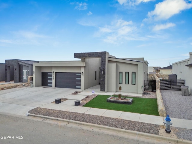 modern home with an attached garage, fence, concrete driveway, and stucco siding