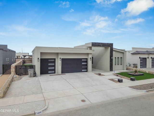 contemporary house featuring a garage, fence, concrete driveway, and stucco siding