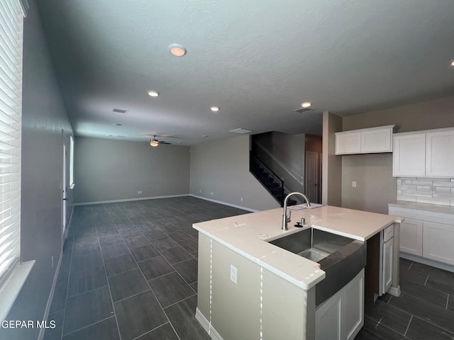 kitchen with white cabinetry, a ceiling fan, backsplash, and a sink