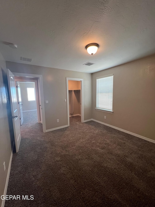 unfurnished bedroom featuring baseboards, visible vents, a textured ceiling, and carpet flooring