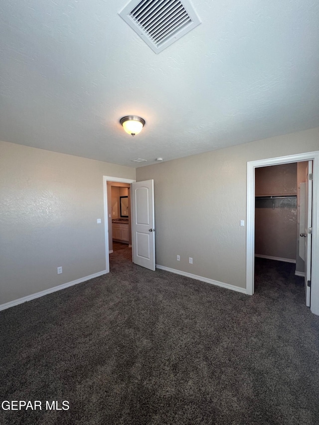 unfurnished bedroom featuring baseboards, visible vents, a spacious closet, and carpet flooring