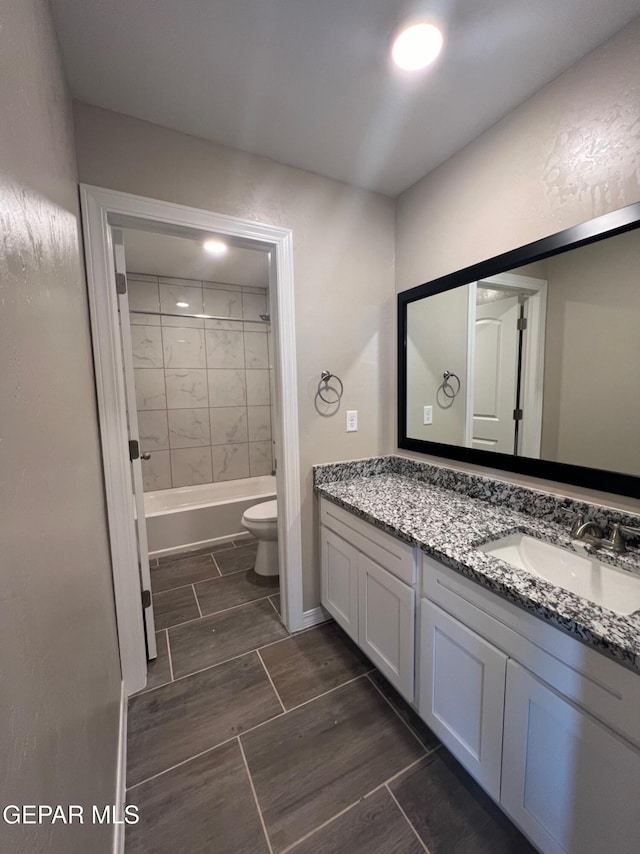 bathroom with toilet, wood finish floors, shower / bath combination, and vanity