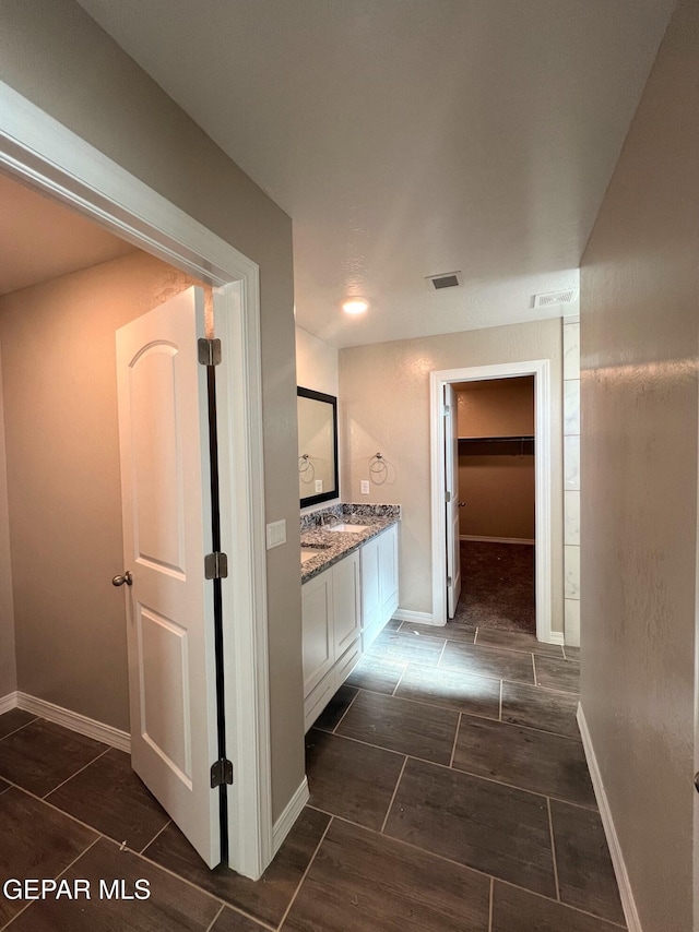 hall with wood tiled floor, visible vents, and baseboards