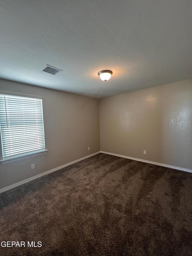 carpeted spare room with a textured ceiling, visible vents, and baseboards