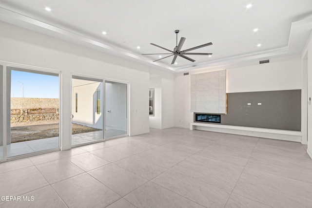 unfurnished living room featuring ceiling fan, recessed lighting, visible vents, a tray ceiling, and a tiled fireplace