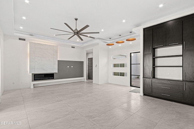 unfurnished living room with a tray ceiling, a tiled fireplace, visible vents, and recessed lighting