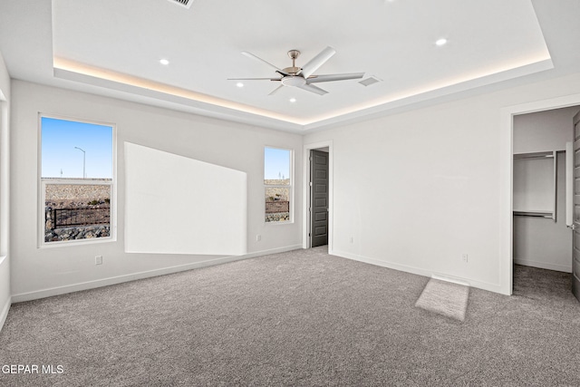 unfurnished bedroom featuring carpet floors, recessed lighting, a raised ceiling, and baseboards