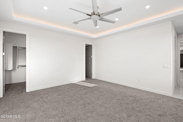 unfurnished room with a tray ceiling, baseboards, and carpet