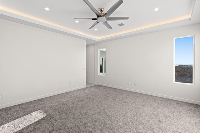 spare room featuring baseboards, a raised ceiling, and recessed lighting